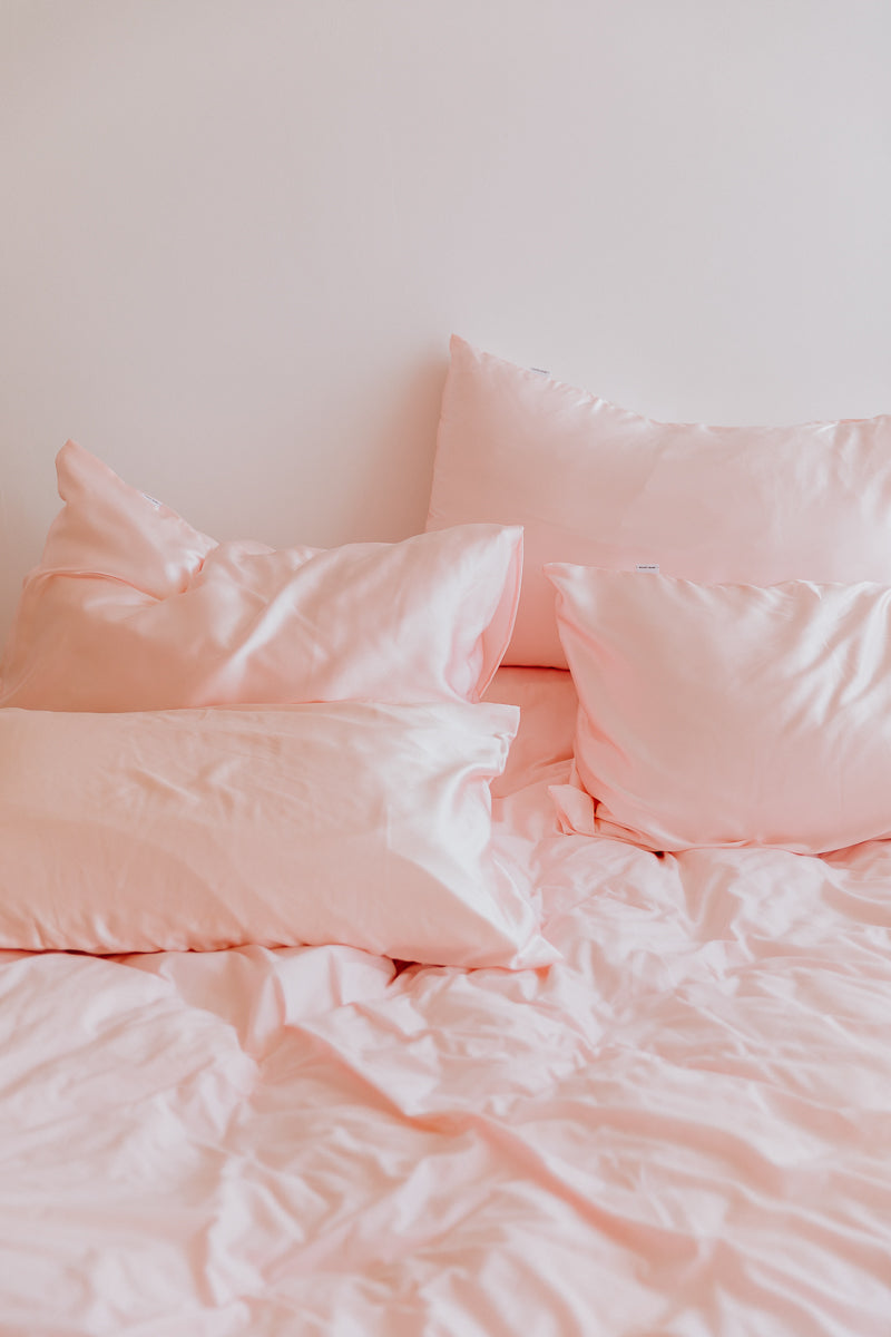 bed with blush pink silk pillowcases